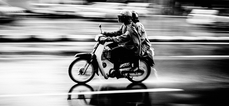 Couple riding motorcycle in the street in black and white panning photography photo.