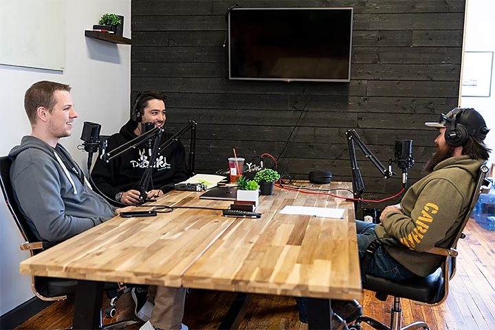 Three people sitting around a table recording a podcast video