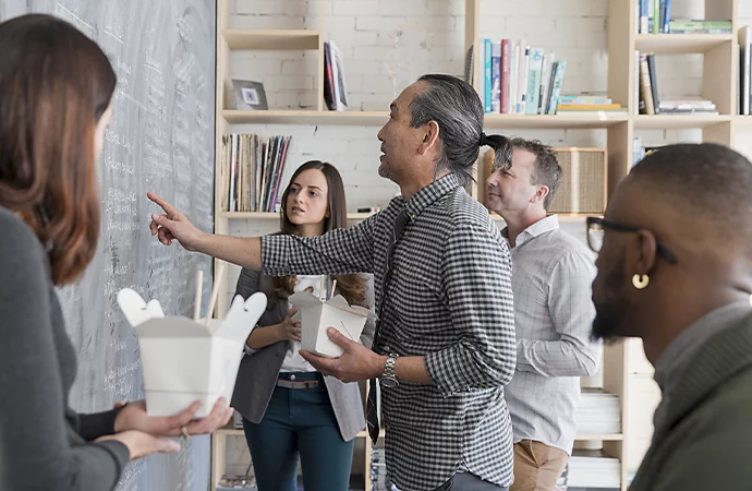 Adeptes de la réflexion conceptuelle en pleine séance de brainstorming sur un tableau noir