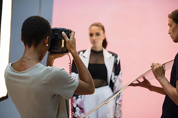 A candid photo of a photographer shooting a portrait of a fashion model.