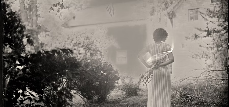 A vintage photo of a person standing in a garden