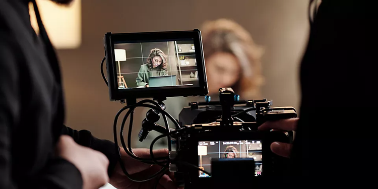 Een videoscherm waarop een raster voor de beeldverhouding wordt getoond met een afbeelding van een vrouw die aan een bureau zit met een laptop.