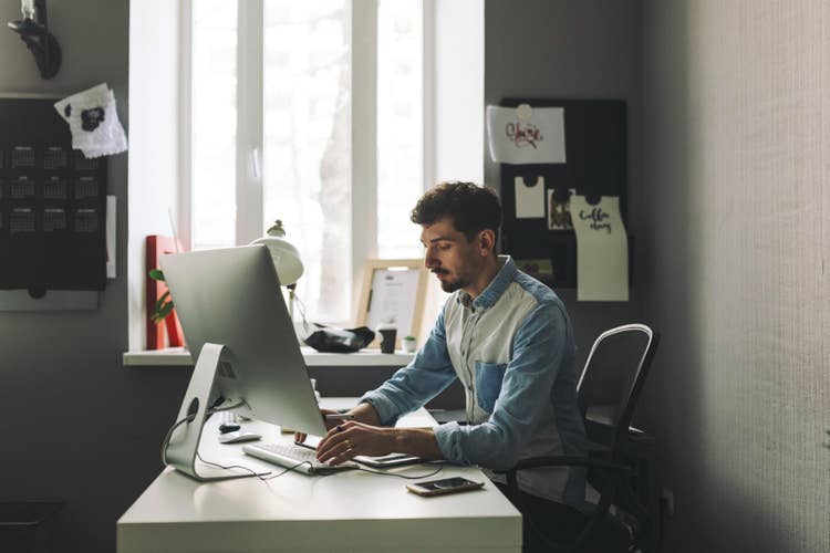 Man working on his office table using his computer