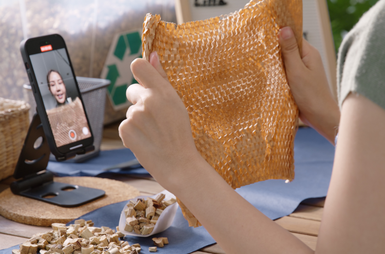 Creating a TikTok A young woman records herself as she holds up a piece of brown fabric to the camera.