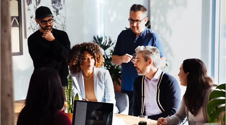 A group of colleagues sits around a table having a discussion.