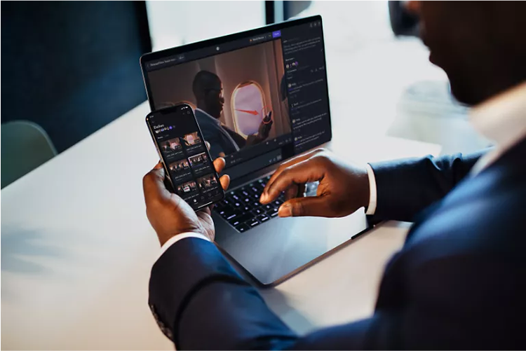 A man looks at the Frame.io editing panel on his phone and computer.