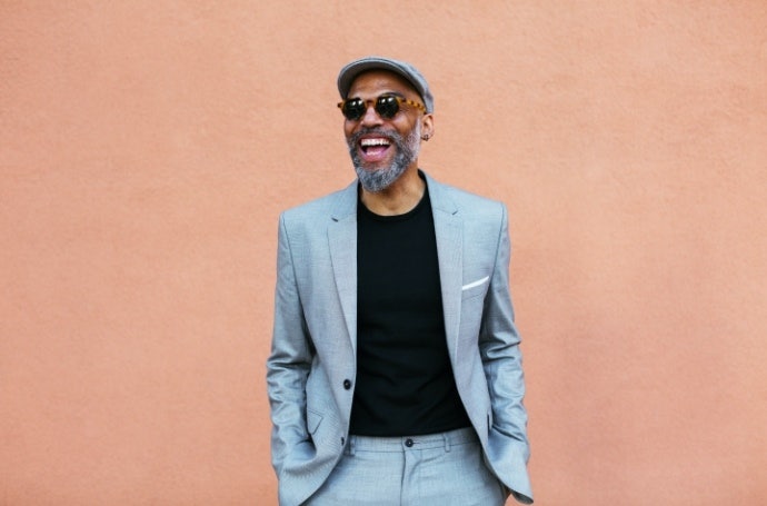 Man wearing sunglasses and suit in front of a pink background