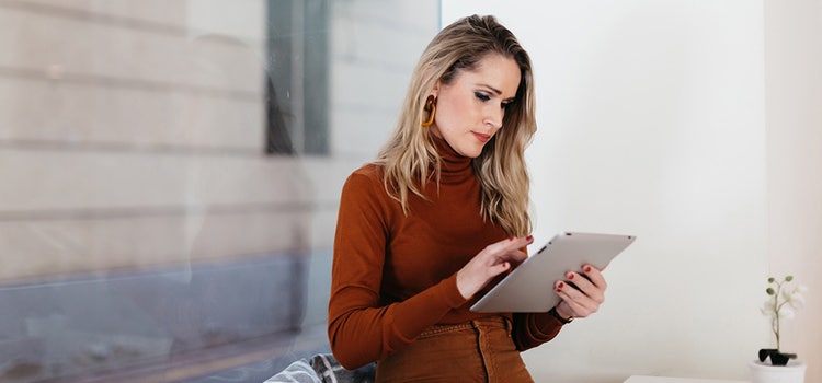 A business owner standing and using a tablet computer in their office