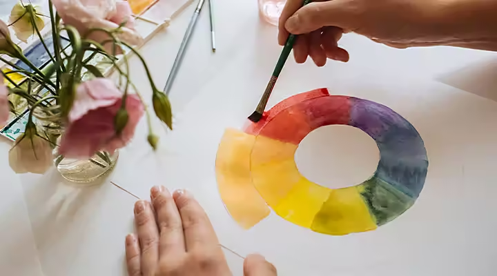 A person watercoloring a color wheel