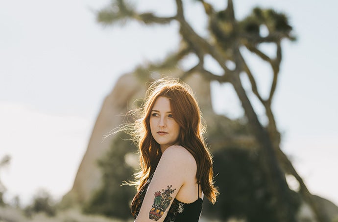 Beautiful, short depth of field picture of an auburn-haired, tattooed woman