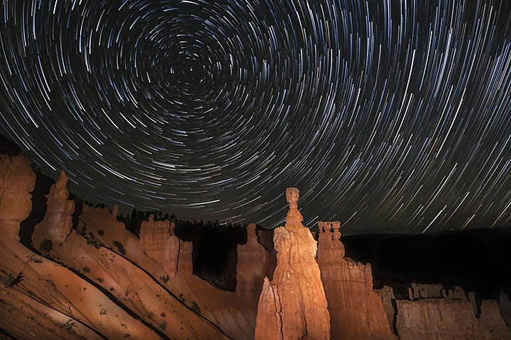 Star trails behind a rocky canyon