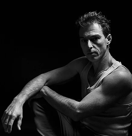 Shadowy features of a male model sitting in low light