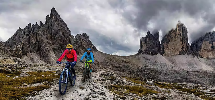 Mountain bikers ride along a rough path with mountains in the distance as part of a sizzle reel