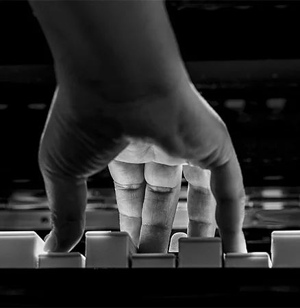 Low light image of a pianist's fingers as they tickle the ivories