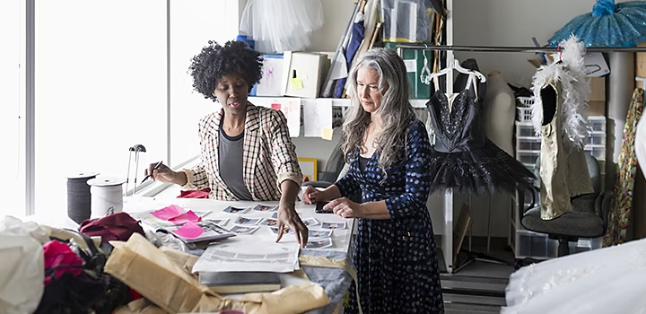 Two production workers reviewing people's profiles in a wardrobe room