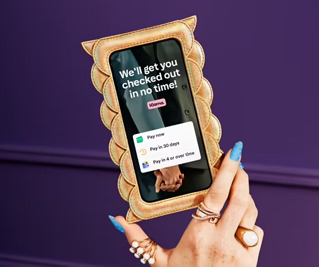 A phone pictured with the Klarna interface that reads 'We'll get you checked out in no time!'