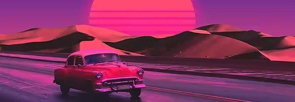 Saturated image of a vintage sedan driving by sand dunes with a setting sun in the background.