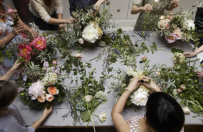 People putting together numerous bouquets of flowers