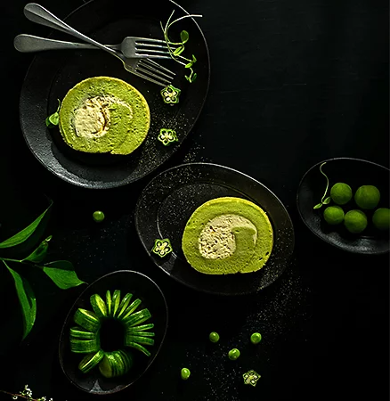 Green food on top of black dishware in front of a black background