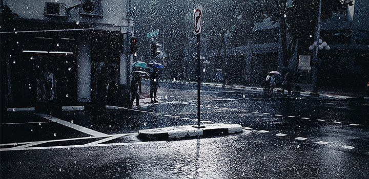 A photo of people with umbrellas standing on a rainy city street.