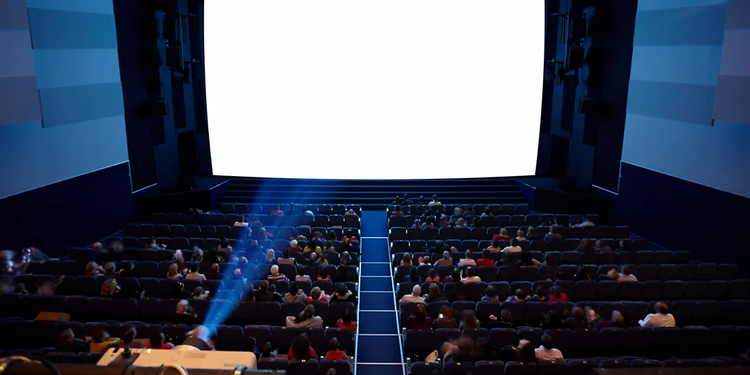 Cinema tinteggiato di rosso con sedie blu come esempio del vantaggio dei formati ampi sugli schermi grandi.