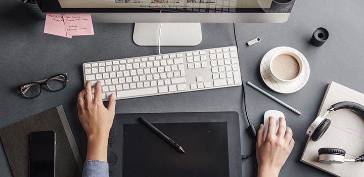 Una persona trabajando con su computadora con una taza de café.