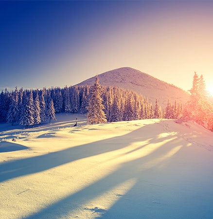 Dazzling nature photo of the sun rising over a snow-covered field.