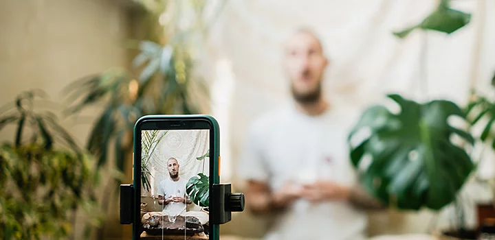 A person using a mobile phone on a tripod to take their own professional headshot