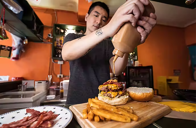 Wide angle photo of a person preparing a hamburger dish with fries