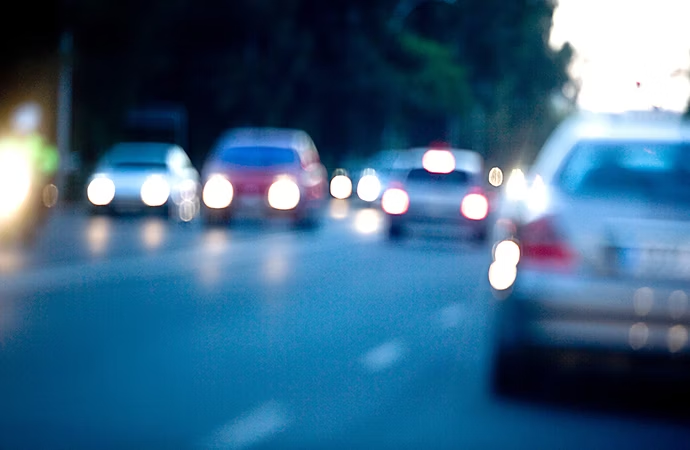 Carros que pasan por dos carriles difuminados para resaltar los faros blancos