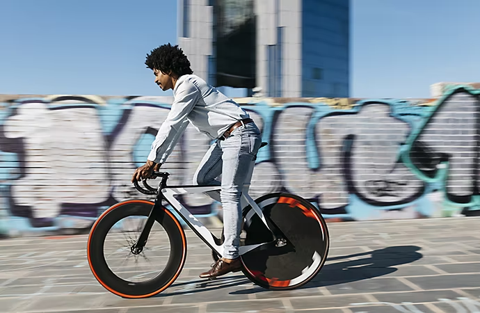 Hombre en una bicicleta pasando por delante de una imagen desenfocada de una pared de ladrillos con grafitis