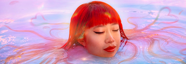 A woman with red hair floating in water