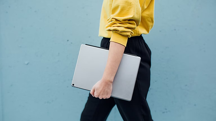 Person walking by holding a laptop