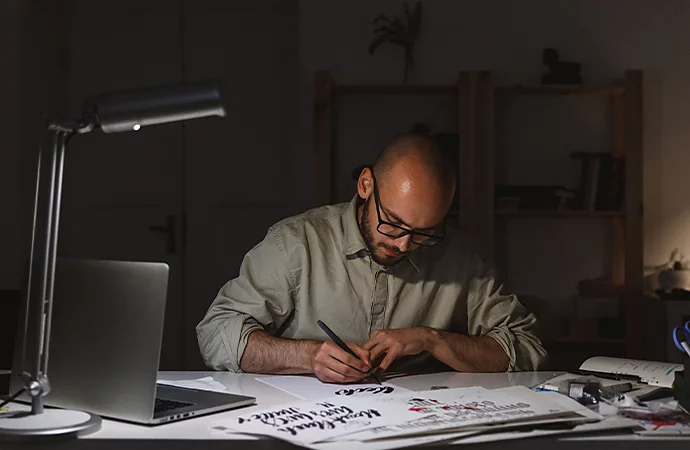 A designer sketching various vintage logo designs at their desk