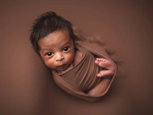 A photo of a newborn baby wrapped in a fabric.