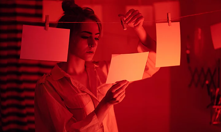 A photographer reviewing an image in their darkroom to make sure it is sepia