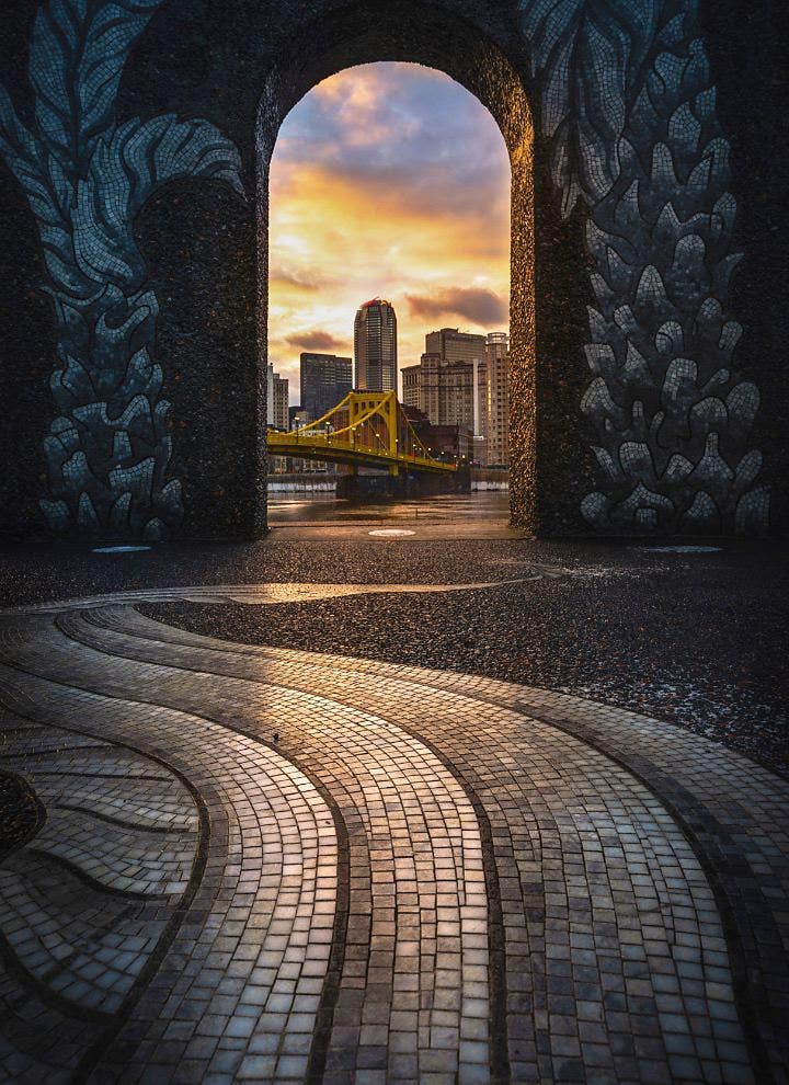 HDR photo of a bridge connecting to a city seen through a door arch