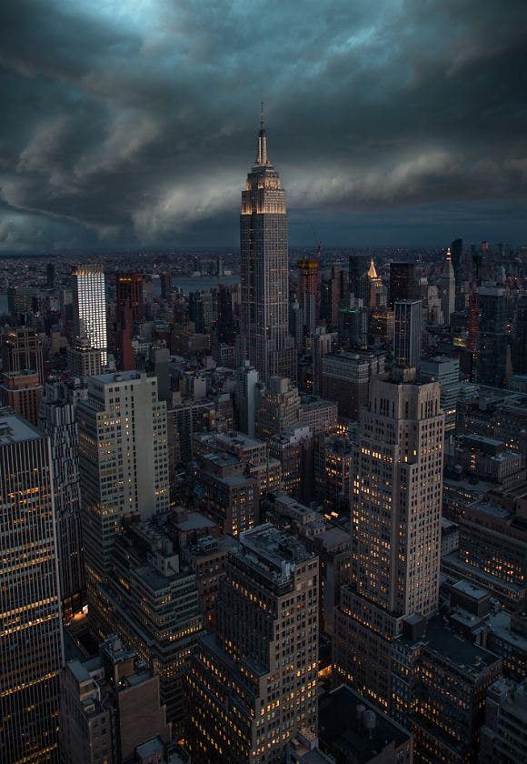 The Empire State Building standing tall and proud among smaller buildings in a dark gray cityscape