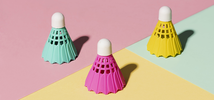 Three brightly colored badminton shuttlecocks on a pastel background in an example of minimalist photography