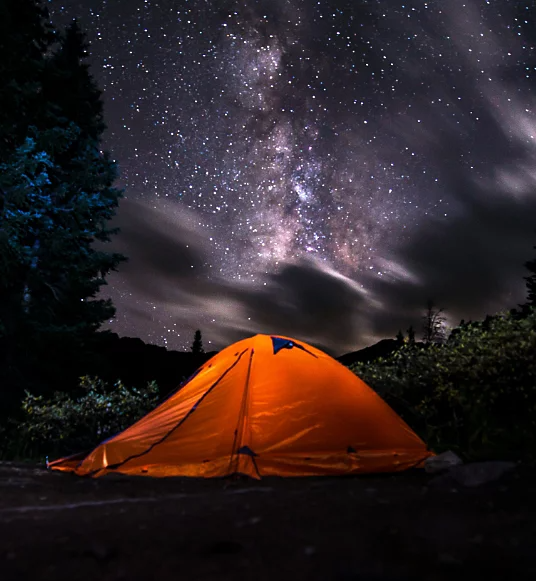 A photo of a camping tent at night. The sky is full of stars.