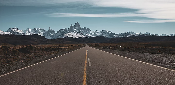 An open road heading toward a snow-covered mountain