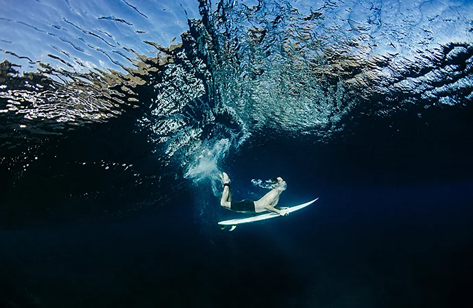 An underwater photo of a surfer riding a board through a wave