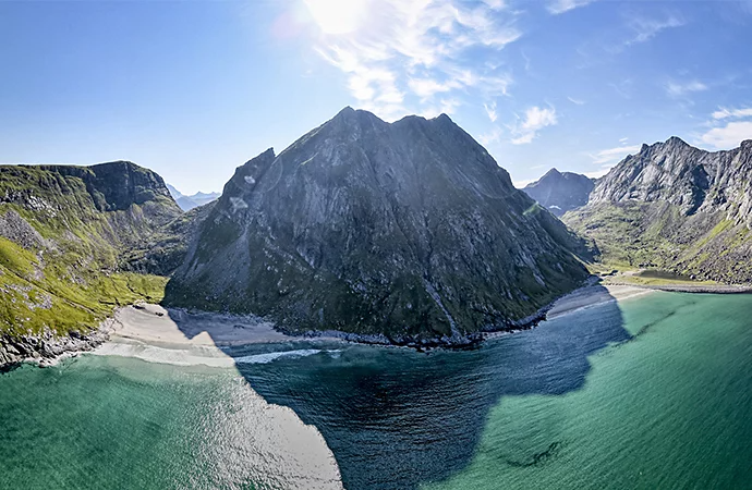 A mountain in front of an ocean shoreline