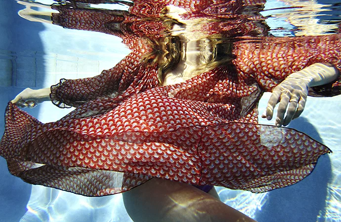 An underwater photo of a person wearing a dress in a pool