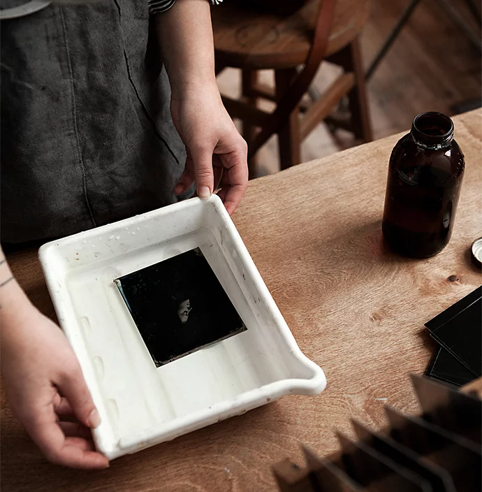 A photographer preparing a tintype photo in a solution