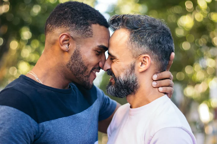 An engagement picture of a couple standing forehead-to-forehead.