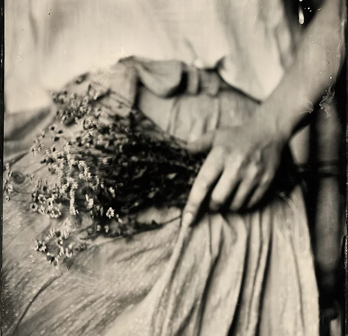 A tintype photo of a person holding a flower bouquet