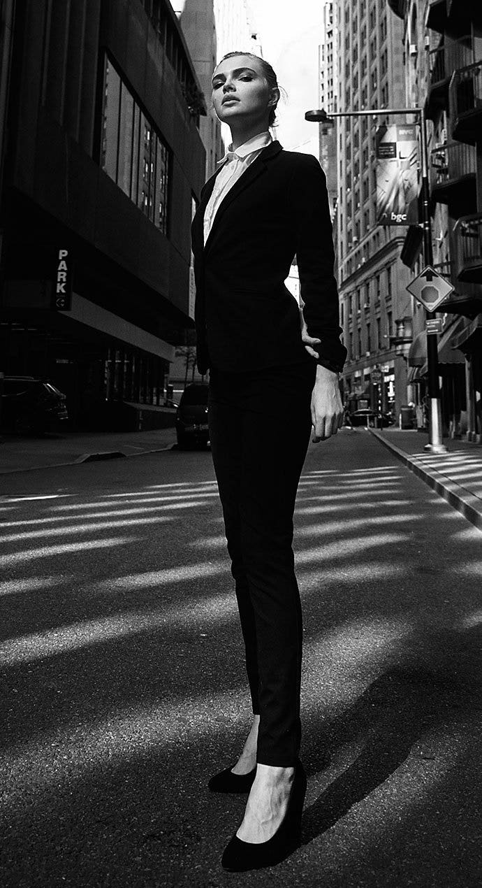 A black-and-white photo of a person wearing a dress suit and standing in an empty city street