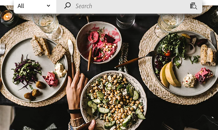 Overhead stock photo of a Mediterranean feast with an Adobe Stock search bar overlaid at the top