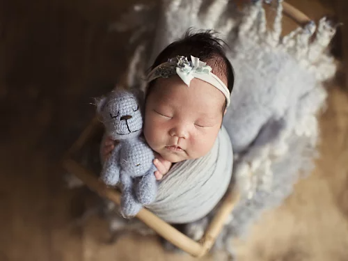 A photo of a newborn baby holding a stuffed animal.